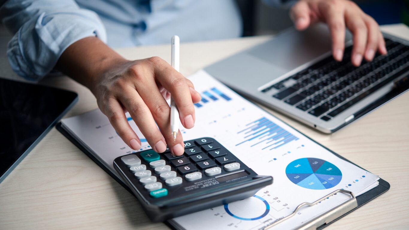 Close-up of financial reports, calculator, and laptop used for business valuation review.