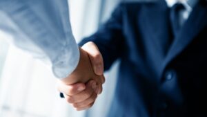 Close-up of two business professionals shaking hands after a transaction discussion.