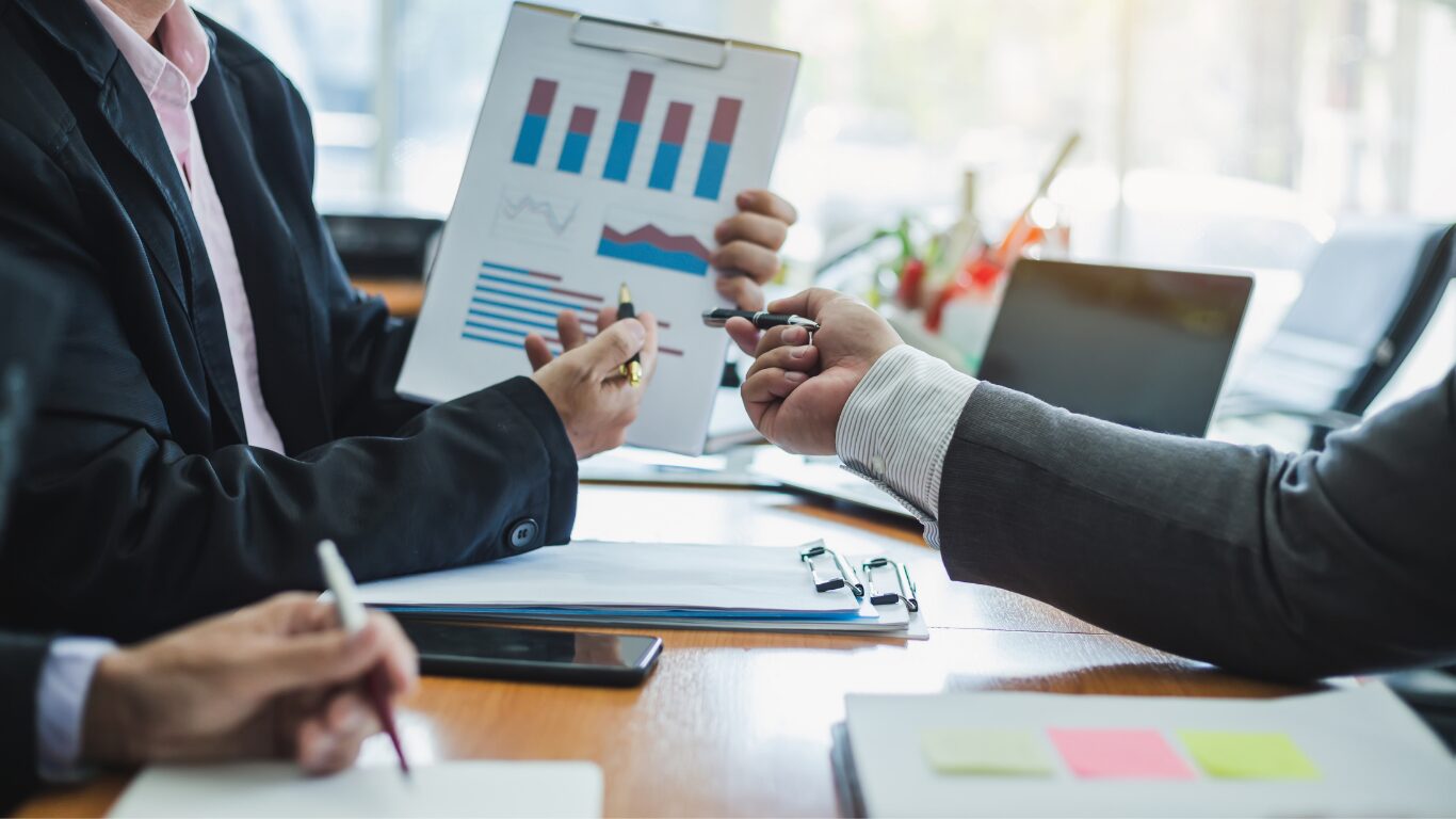 Business advisors reviewing charts and valuation data during a financial discussion.
